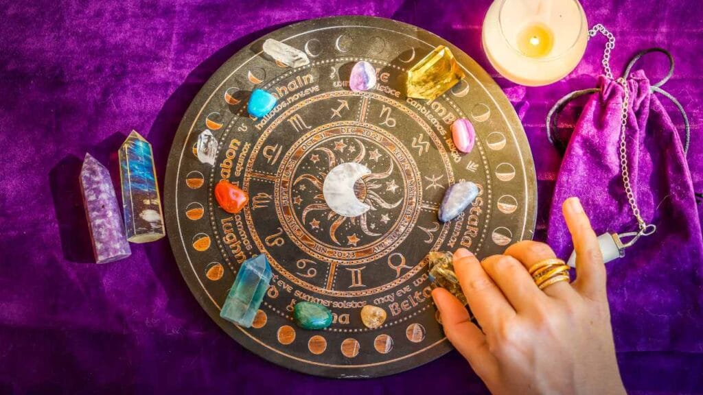Mesa com pessoa praticando a magia planetária por meio de símbolos e cristais